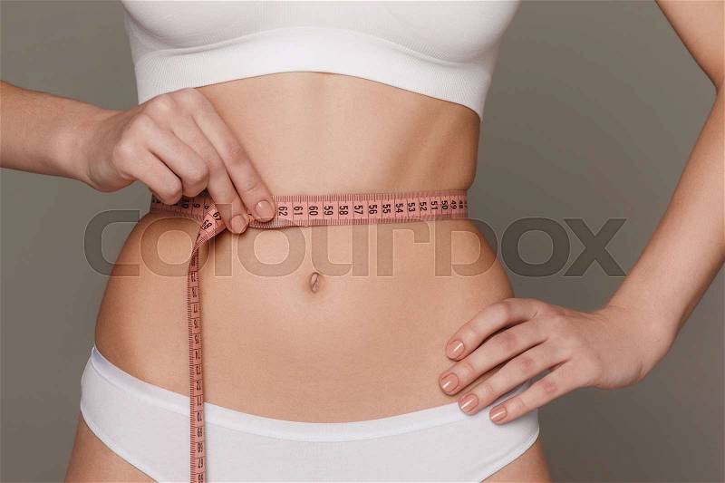 The girl taking measurements of her body, white studio background, stock photo