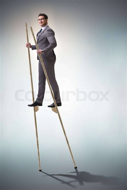 Businessman walking on stilts - standing out from the crowd, stock photo