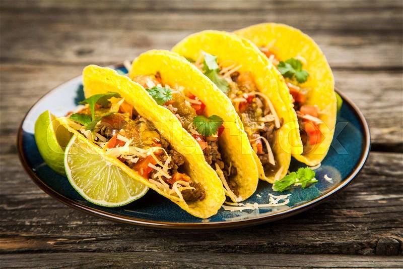 Mexican tacos with beef, cheese, tomato and green salsa, stock photo