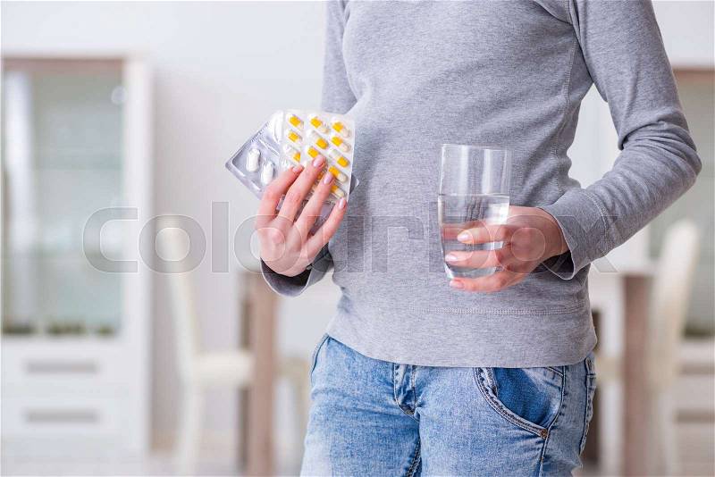 Pregnant woman taking pills during pregnancy, stock photo