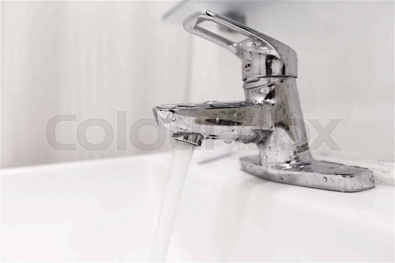 Bathroom water faucet with water running, selective focus, stock photo