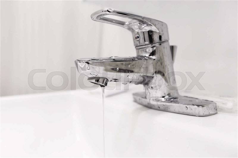 Bathroom water faucet with water leak running, stock photo