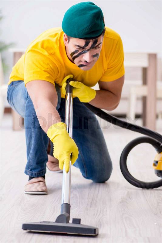 Funny man in military style cleaning the house, stock photo