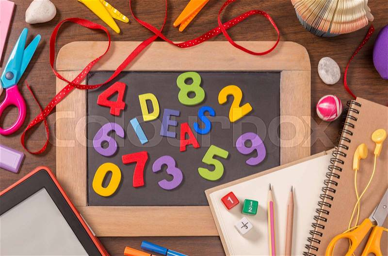 Ideas word formed by color wooden alphabets on small blackboard with school supplies on wooden table, stock photo