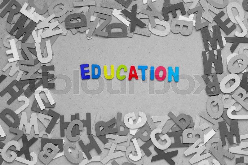 Education word formed by colorful wooden alphabets, surrounded by random colorful alphabets on wooden background, stock photo
