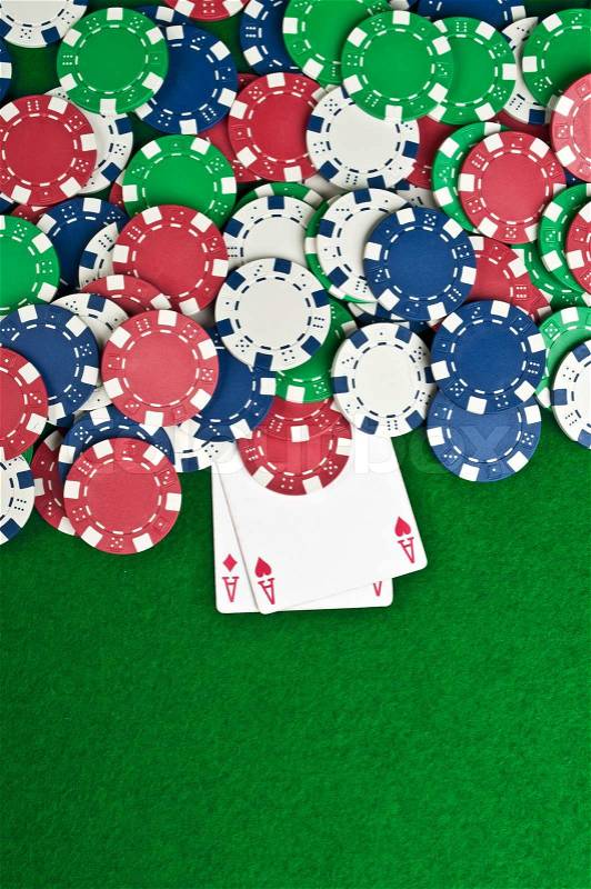 Two aces and poker chips on a green felt, stock photo