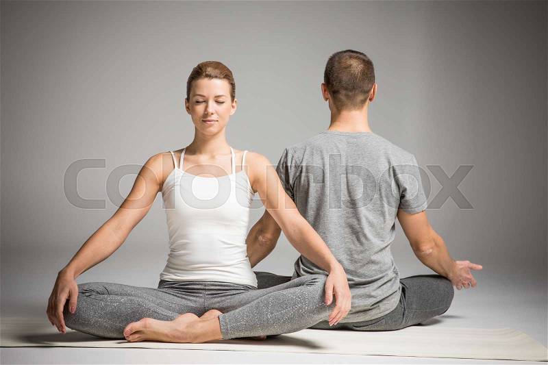 Young couple practicing yoga sitting in lotus position on yoga mats , stock photo