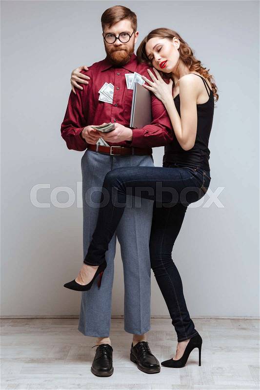 Vertical image of Woman stick to the Male nerd with money, stock photo