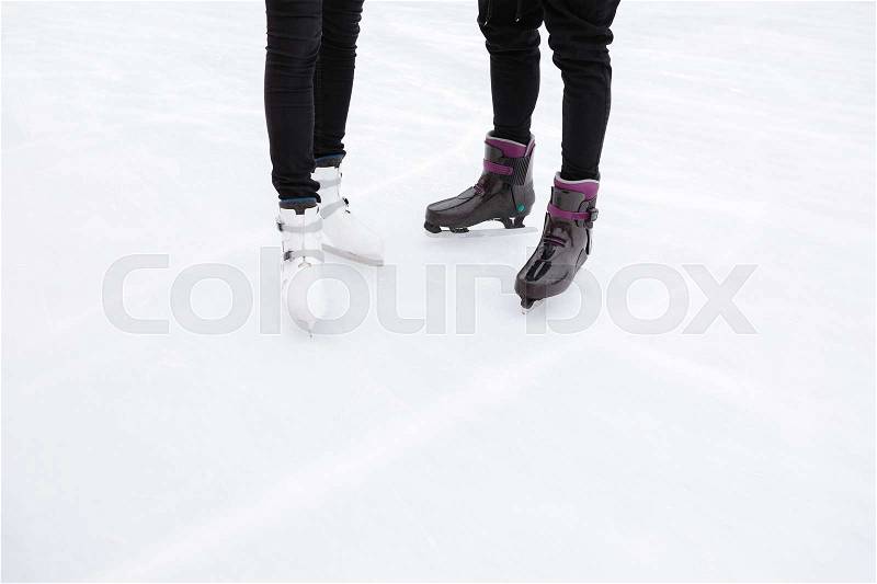 Cropped picture of young loving couple skating at ice rink outdoors, stock photo