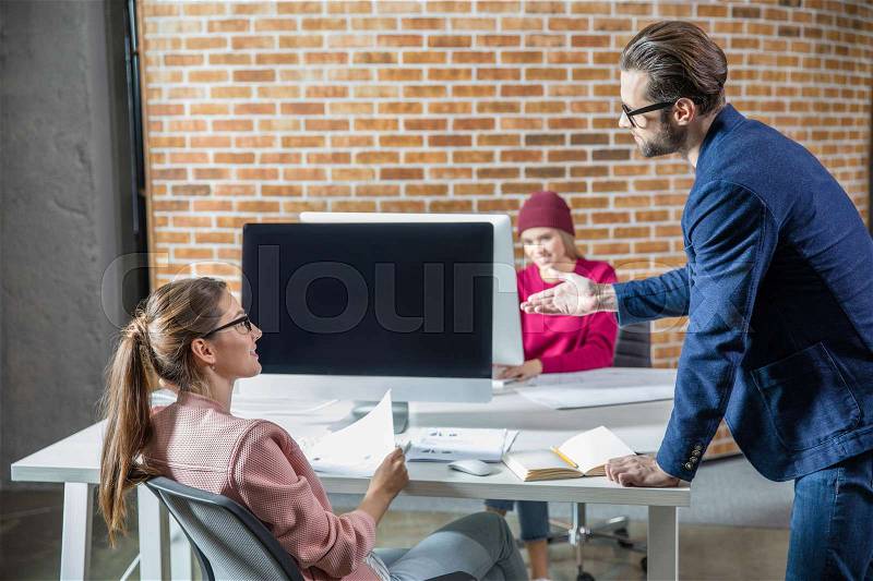 Young man and woman discussing something in modern office, stock photo