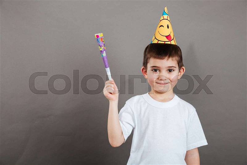 Cute little boy with birthday hat standing and holding whistle, stock photo