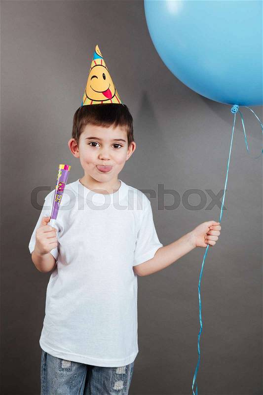Little boy in birthday hat showing toungue and celebrating, stock photo