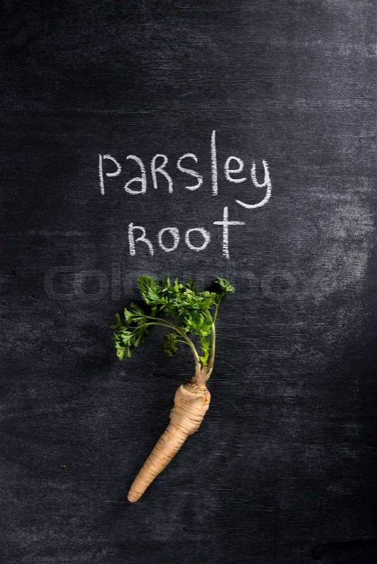 Top view image of parsley root over dark chalkboard background, stock photo