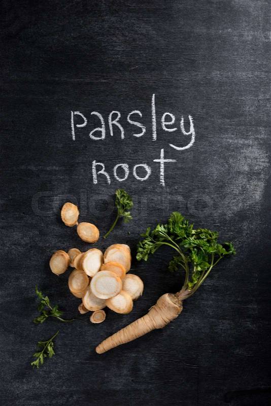 Top view photo of parsley root over dark chalkboard background, stock photo