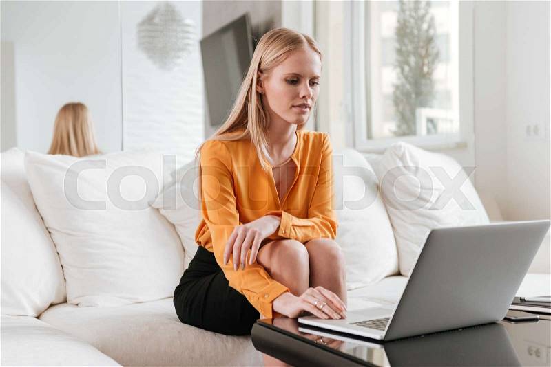 Photo of young pretty business lady sitting in office using laptop computer. Looking at laptop, stock photo