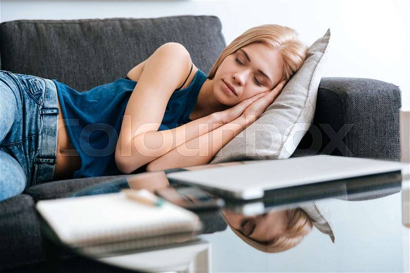 Pretty cute young woman lying and sleeping on couch at home, stock photo
