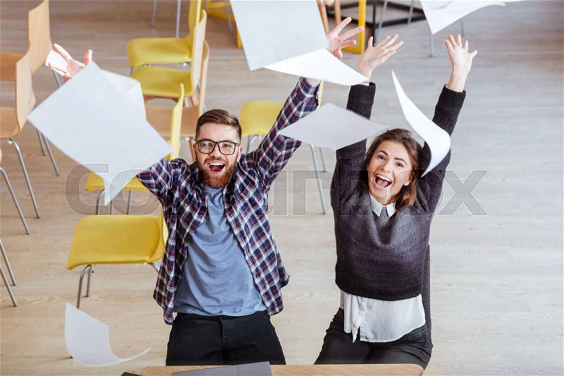 Top view of happy students making mess in library by throwing papers, stock photo