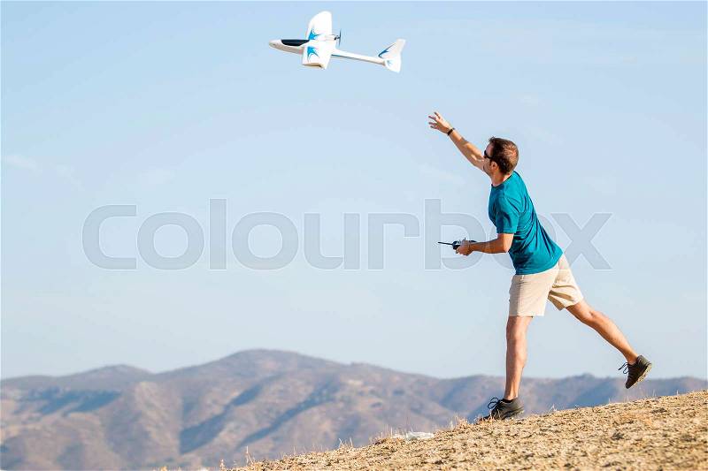 Young man setting remote control plane in air, stock photo