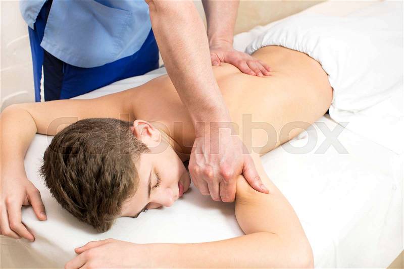 Boy teenager on the procedure of medical medical sports body massage, stock photo