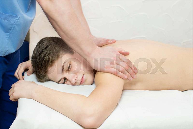 Boy teenager on the procedure of medical medical sports body massage, stock photo