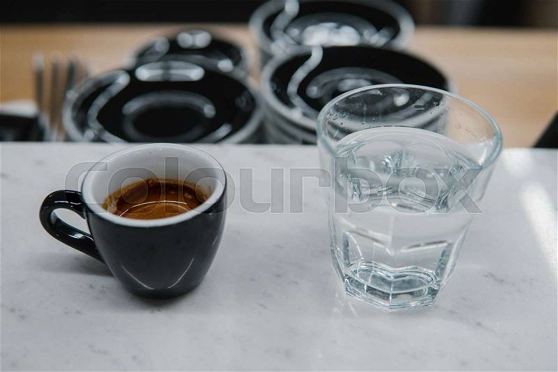 Cup with coffee near a glass of water on the table, stock photo