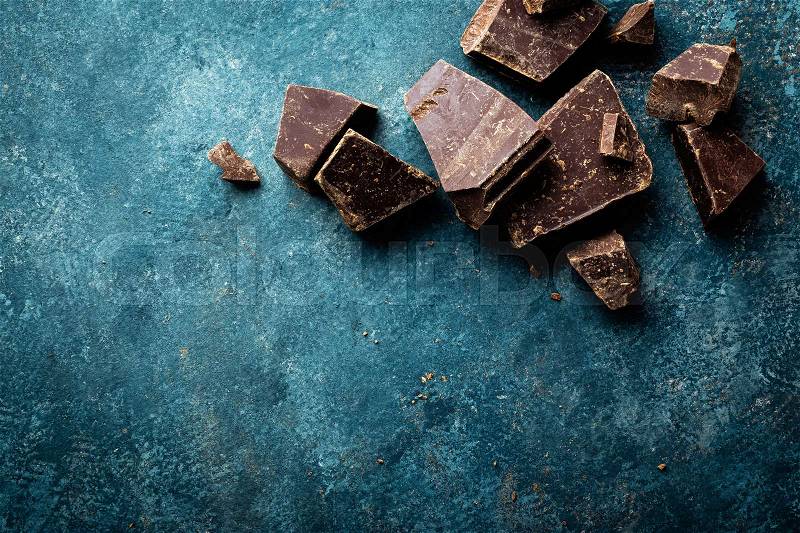 Dark chocolate pieces crushed on a dark background, view from above, stock photo