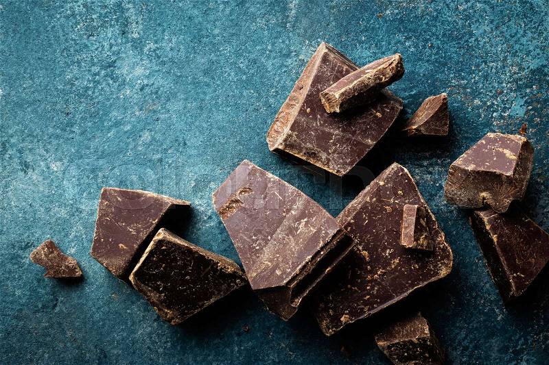 Dark chocolate pieces crushed on a dark background, view from above, stock photo
