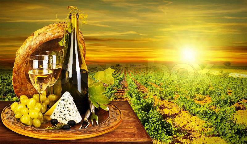 Wine and cheese romantic dinner outdoor, table for two with vineyard view, fresh grapes and wineglass at restaurant, warm autumn sunset, grape field landscape at harvest, food still life, stock photo
