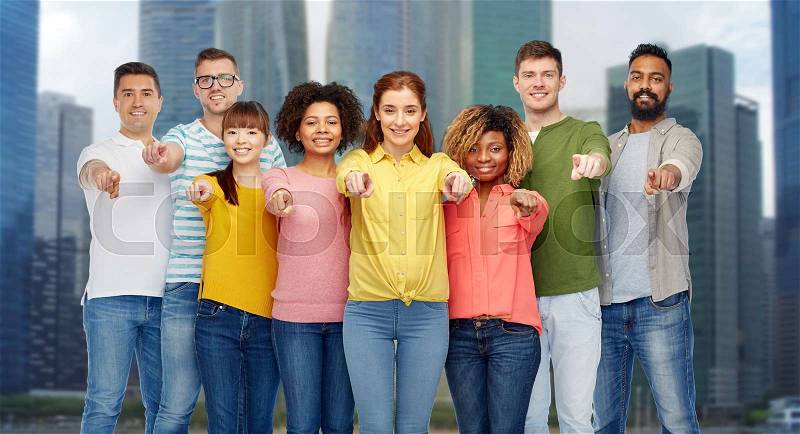 Diversity, choice, ethnicity and people concept - international group of happy smiling men and women pointing finger on you over singapore city skyscrapers background, stock photo