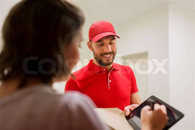 Delivery, mail, people and shipping concept - happy man delivering parcel box and customer signing on tablet pc computer at home, stock photo