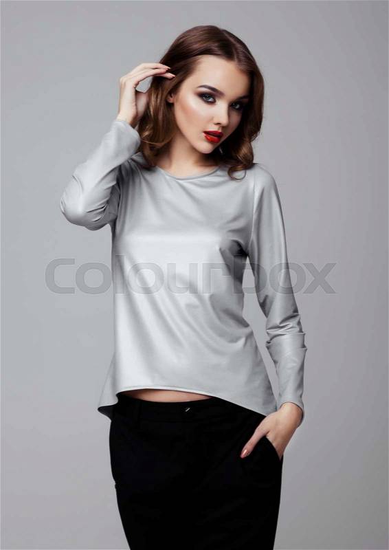 Beautiful fashion model wearing silver top and black on white background, stock photo