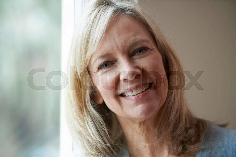 Smiling Mature Woman Standing Next To Window, stock photo