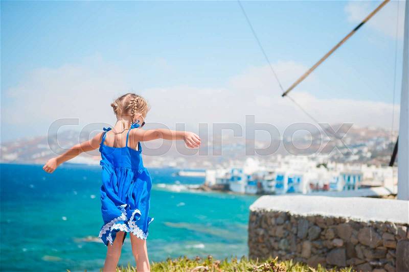 Funny little girl with amazing view on Little Venice the most popular tourist area on Mykonos island, stock photo