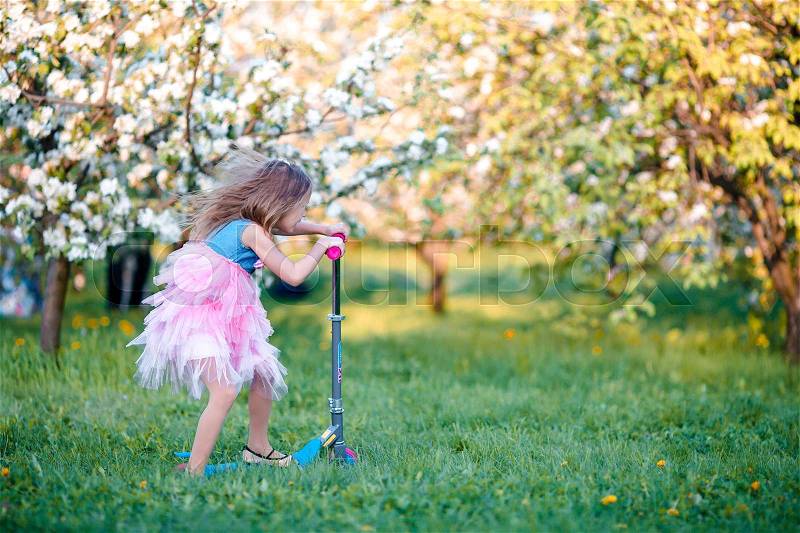 Adorable little girl in blooming apple garden on beautiful spring day, stock photo