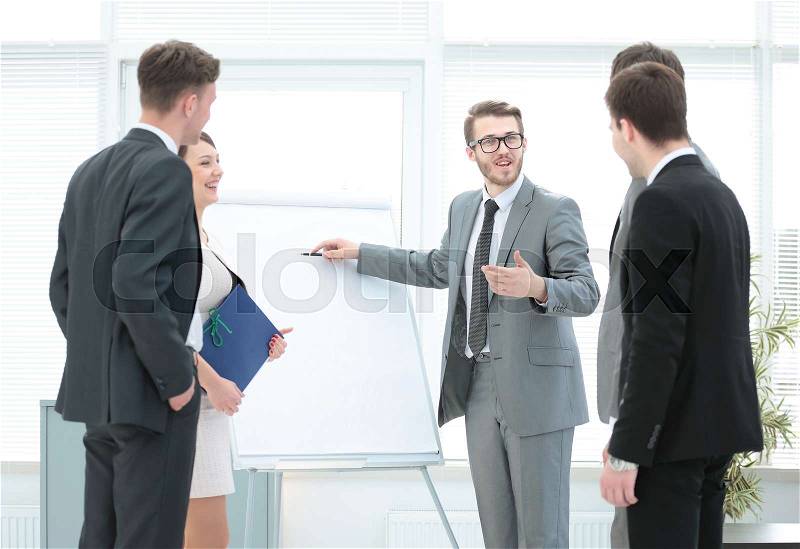 In the middle of the office - a financial Advisor is and shows a poster with the business plan.business team listening to the speaker.the photo is a blank space for your text, stock photo