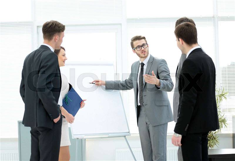 In the middle of the office - a financial Advisor is and shows a poster with the business plan.business team listening to the speaker.the photo is a blank space for your text, stock photo