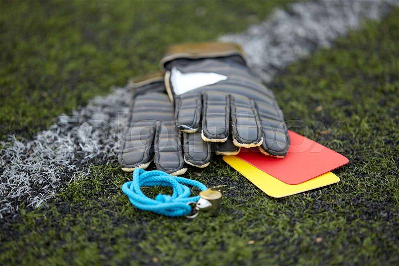 Sport, soccer and game - gloves, goalkeeper referee whistle and caution cards on football field, stock photo