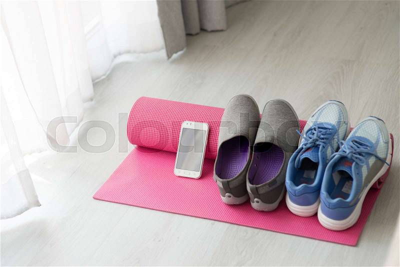 Blue, gray and purple Sport shoes, yoga mat, smartphone on gray background, stock photo