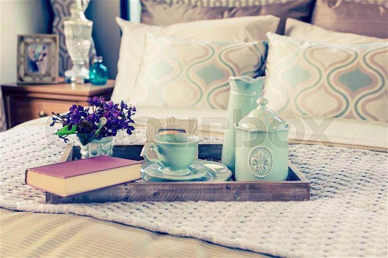 Decorative tray with book,tea set and flower on the bed, stock photo