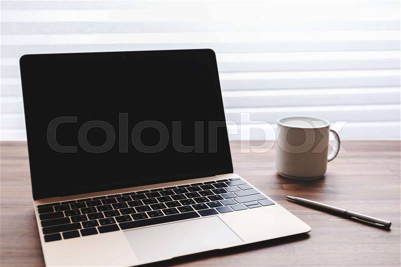 Laptop with pen and coffee cup on office table, stock photo