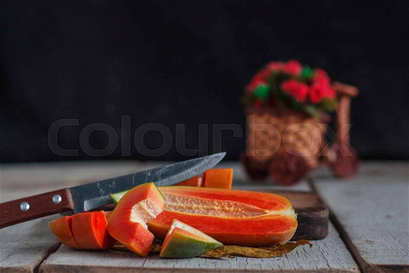 Papaya slices and knife on old wooden floor, stock photo