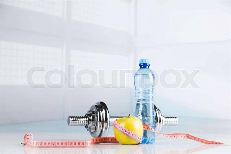 Health and fitness concept with dumbbells, measure tape and fresh fruit, stock photo