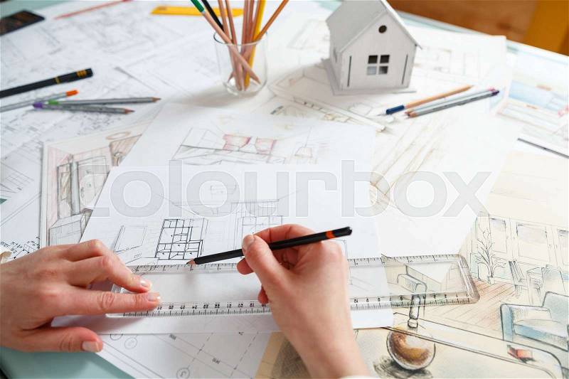 Interior designer working on color hand drawings of a kitchen interior at work place. Photo of young designers work concept, stock photo