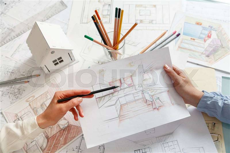 Interior designers working on color hand drawings of a kitchen interior at work place. Photo of young designers work concept, stock photo