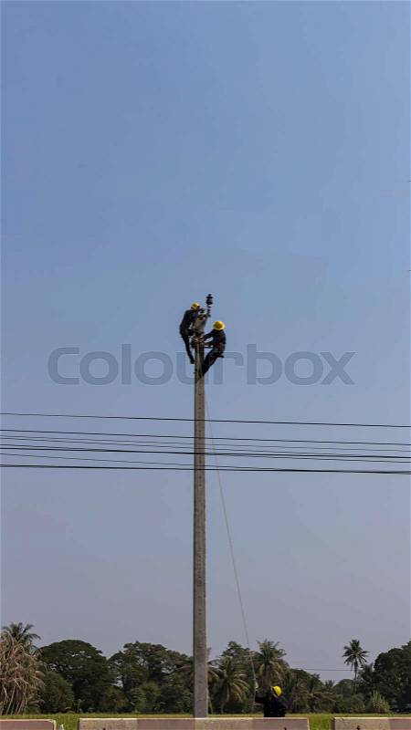 Men install electric cable on the high ground pole, stock photo