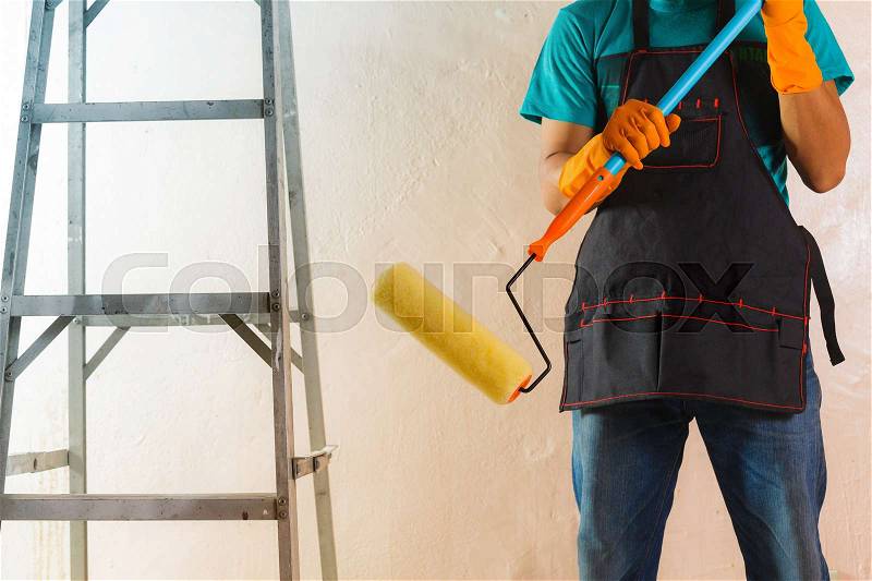 Painter painting the walls white in house, stock photo