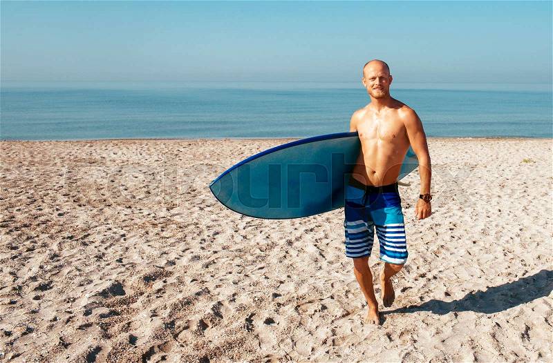 Surfer is going to surf in the ocean in a sunny day, stock photo
