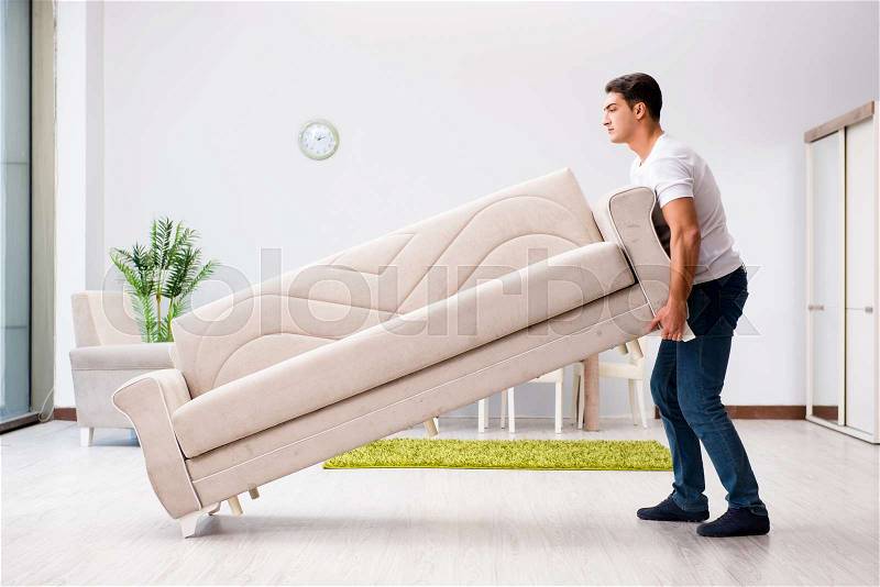 Young man moving furniture at home, stock photo