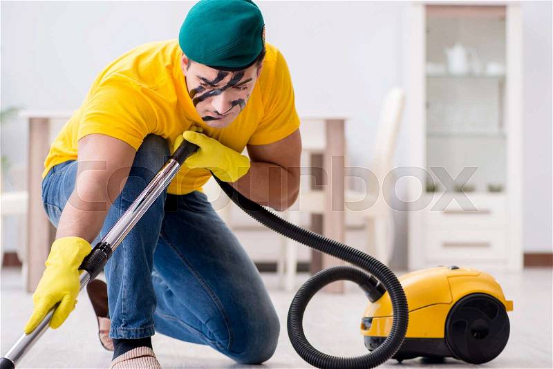 Funny man in military style cleaning the house, stock photo