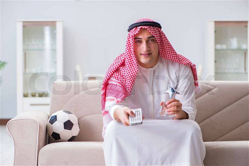 Arab man watching sport football at tv, stock photo